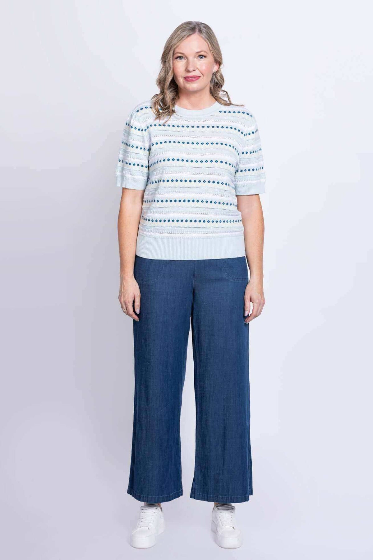 Front view of woman in light blue knit Sweater paired with wide-leg blue pants