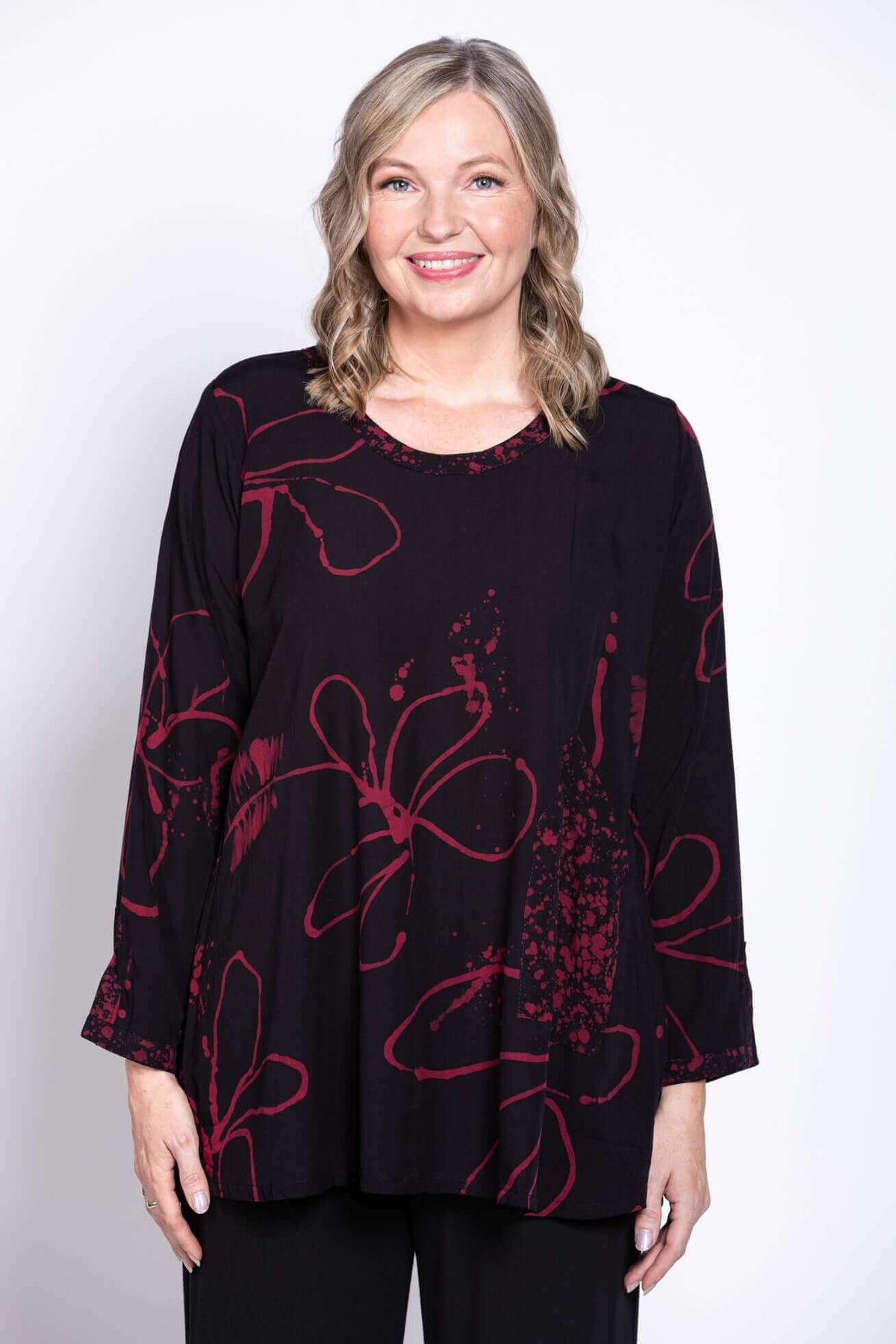 Front view of model wearing black blouse with berry floral print
