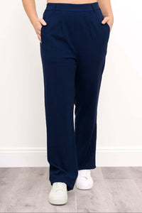 Front view of navy Melodie pants with hands in side pockets and white sneakers