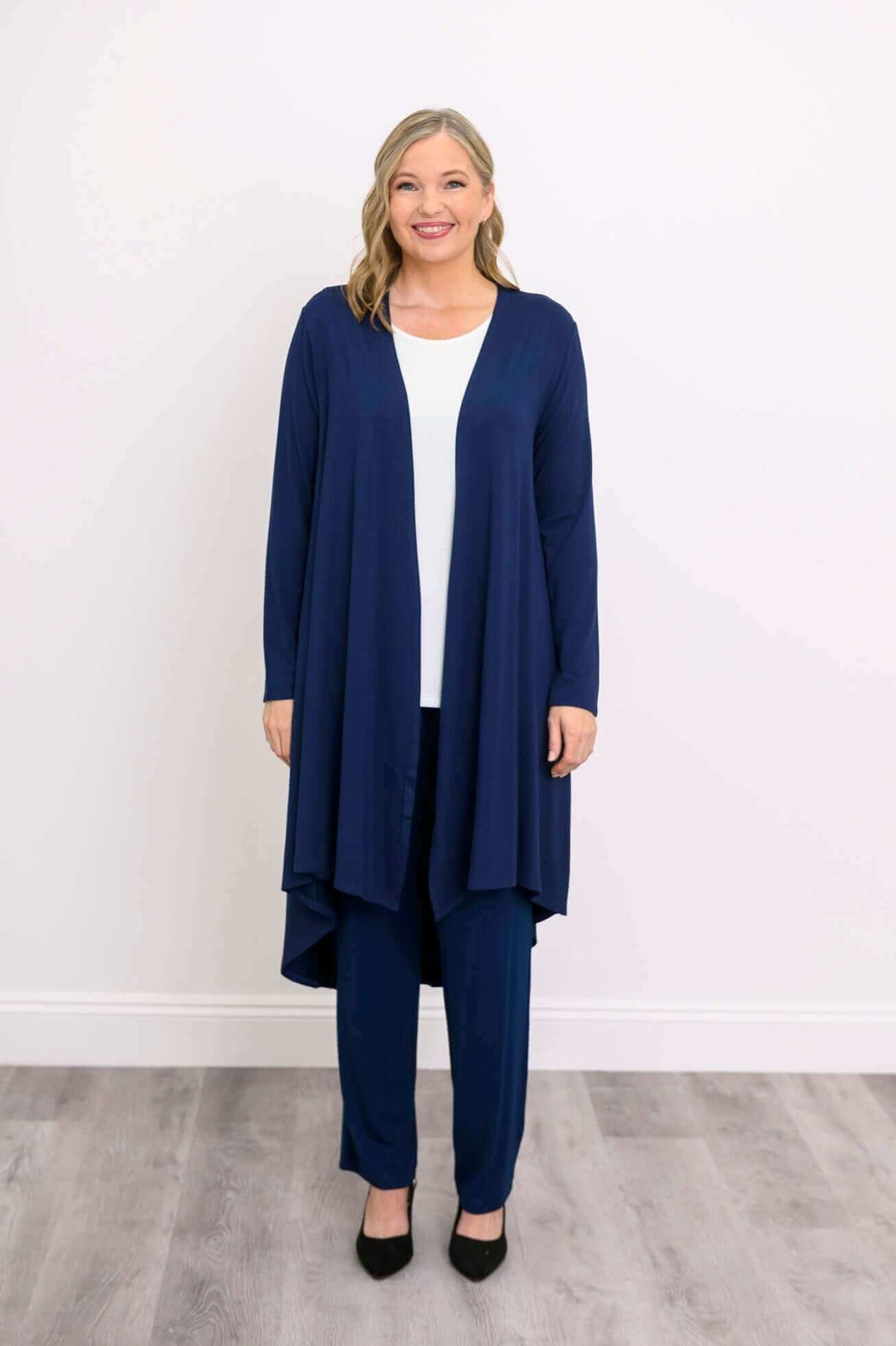 Front view of model in navy blue high-low hem duster with long sleeves