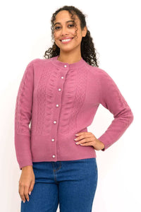 Close up front view of a woman wearing a pink cable knit cashmere cardigan sweater with pearl buttons.
