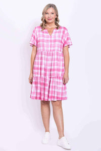 Front view of woman wearing a pink check short sleeve tiered dress with V notch neckline