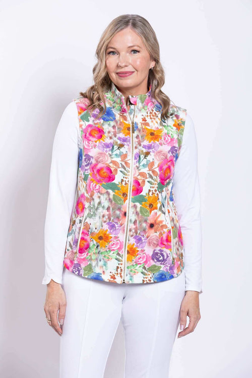 Front view of woman wearing a pink floral print vest with a white long sleeve shirt