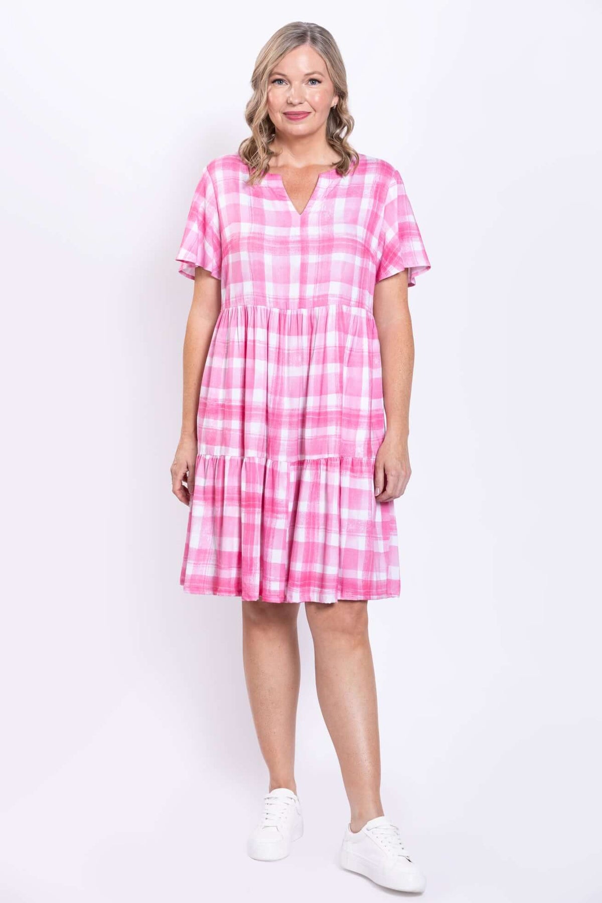 Front view of woman wearing pink gingham tiered dress with short sleeves