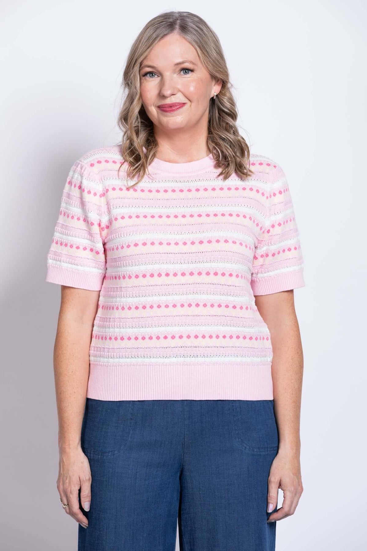 Front view of woman wearing a pink patterned short sleeve knit sweater