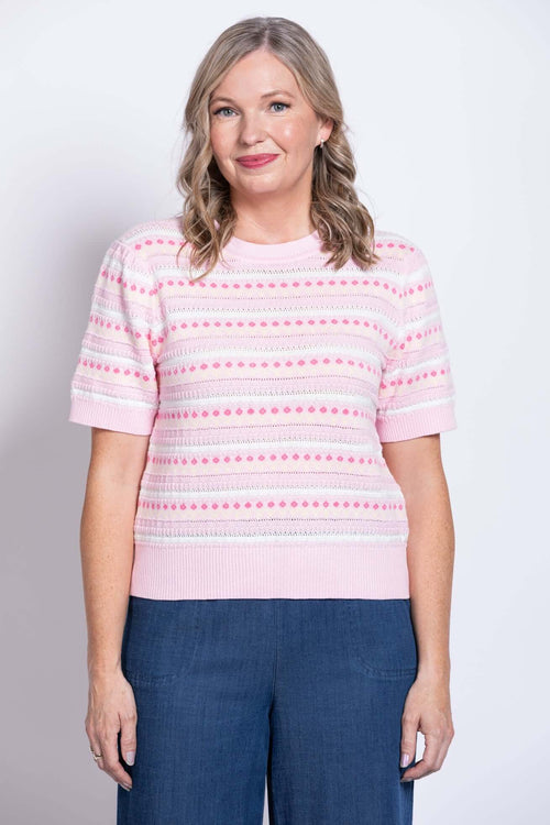 Front view of woman wearing a pink patterned short sleeve knit sweater