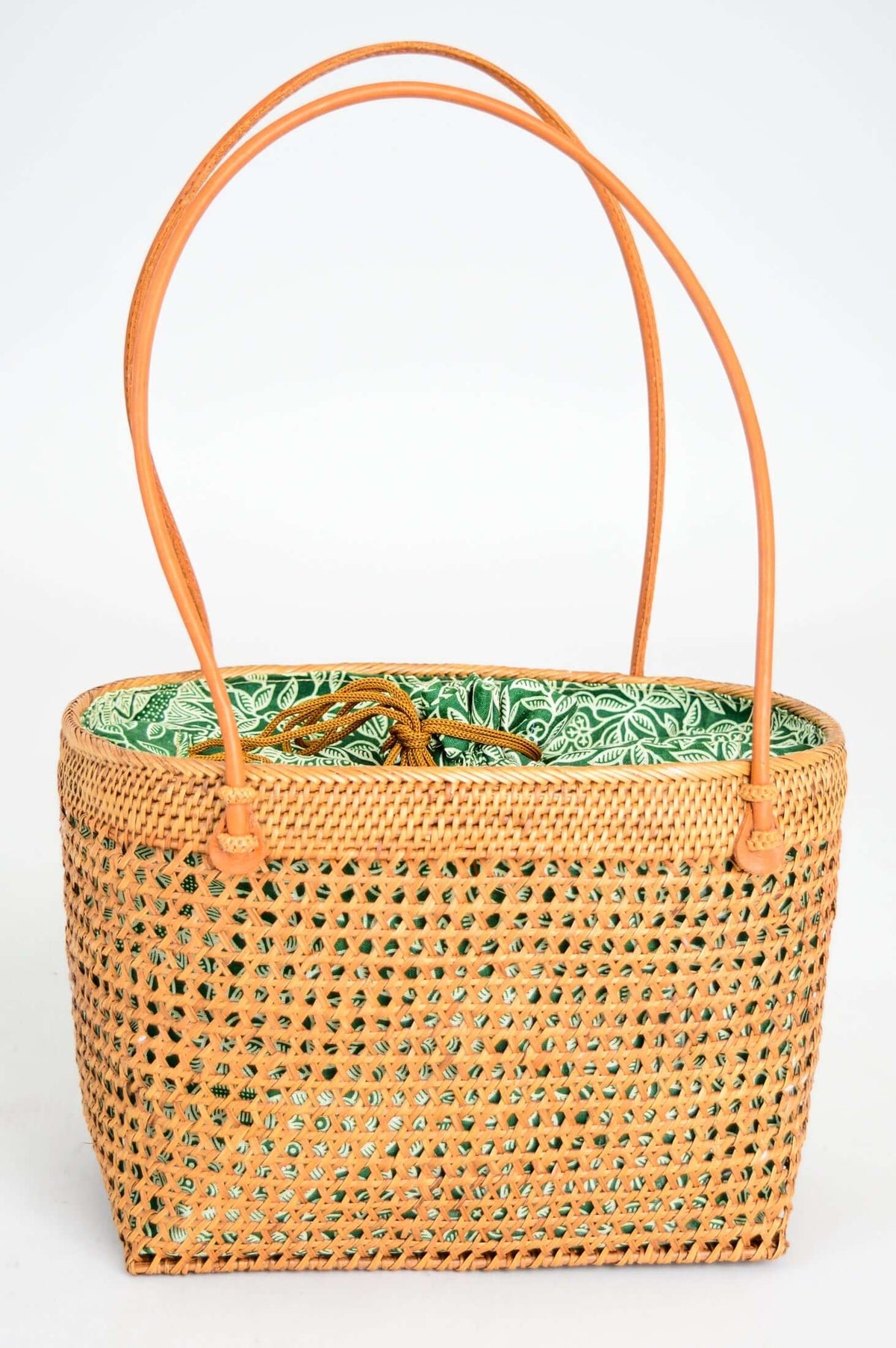 Front view of rattan basket bag with green fabric lining and visible handles