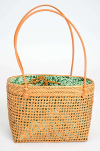 Front view of rattan basket bag with green fabric lining and visible handles