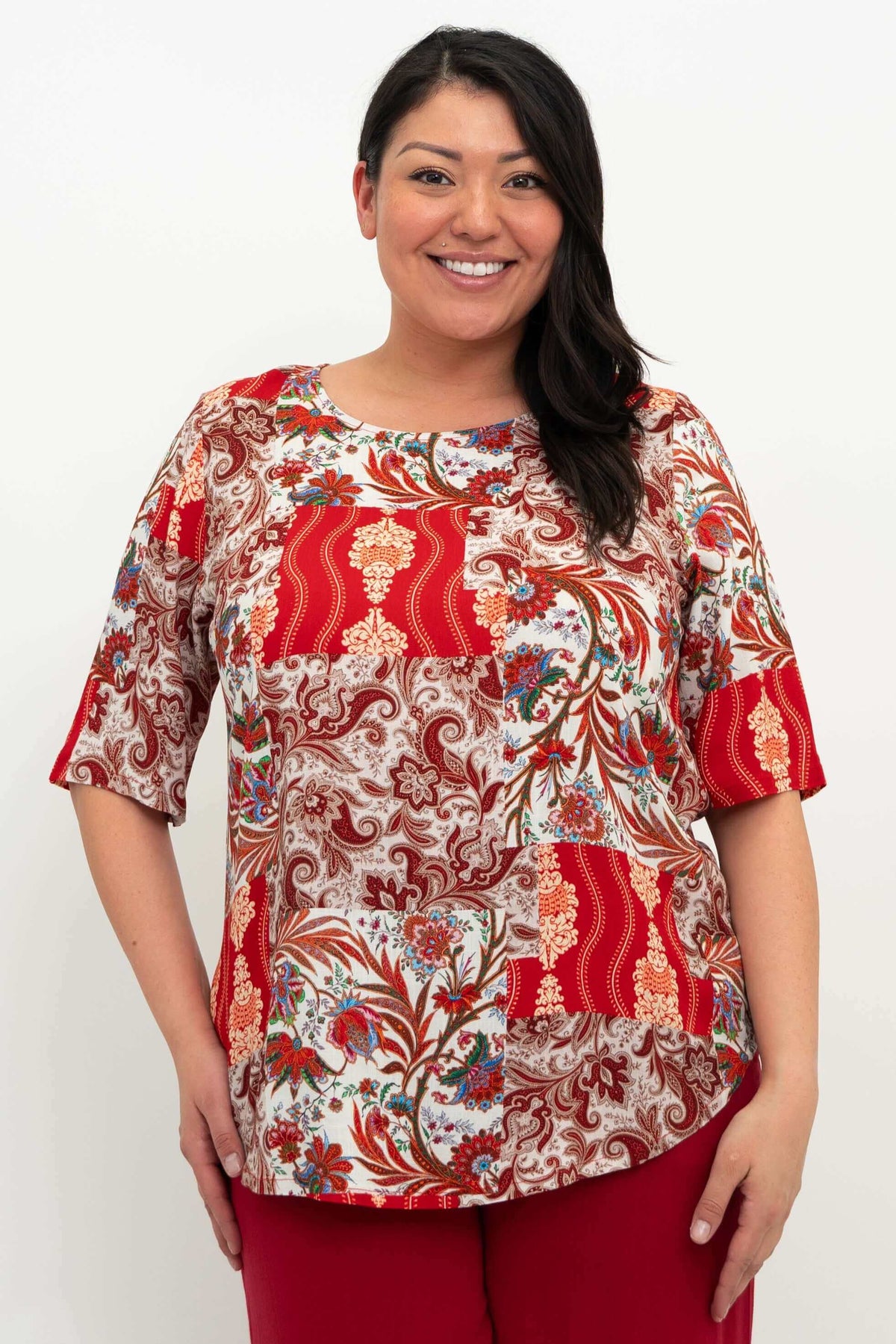 Front view of model wearing a red and multicolor patchwork print blouse