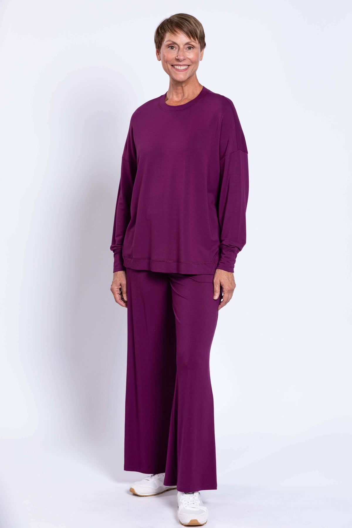 Front view of woman in purple bamboo crew neck top and wide-leg pants, smiling