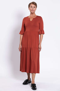 Front view of model wearing rust-colored tiered midi dress with keyhole neckline
