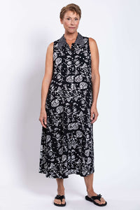 Front view of a woman wearing a sleeveless black A-line dress with white floral patterns