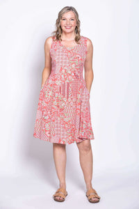Woman wearing a sleeveless coral floral patchwork dress with pockets, front view