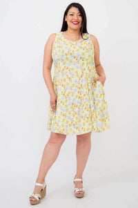Front view of model wearing a sleeveless floral yellow summer dress with pockets
