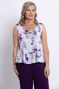 Front view of a woman wearing a sleeveless white tank with purple floral print and purple pants