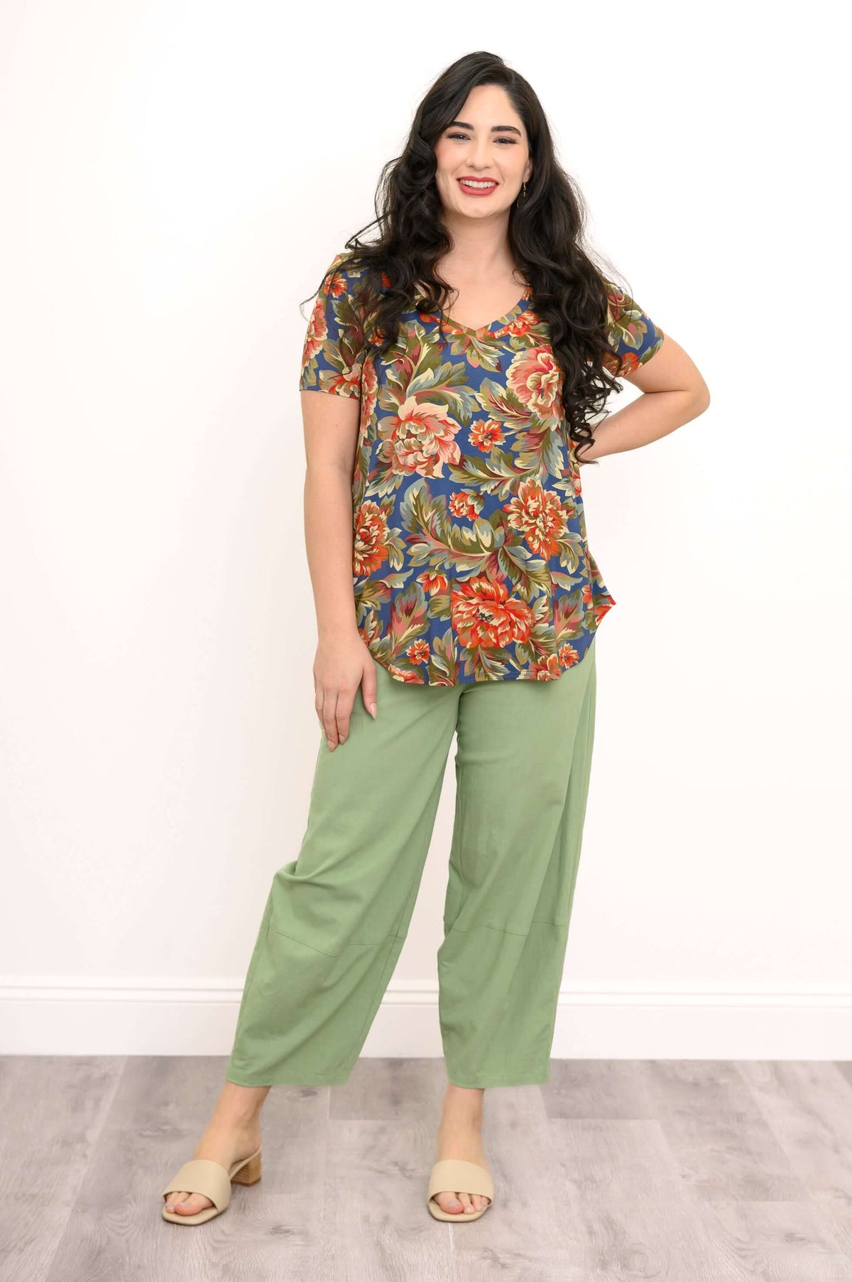 Front view of smiling woman in Jackie Bamboo V-Neck Floral Top and green pants