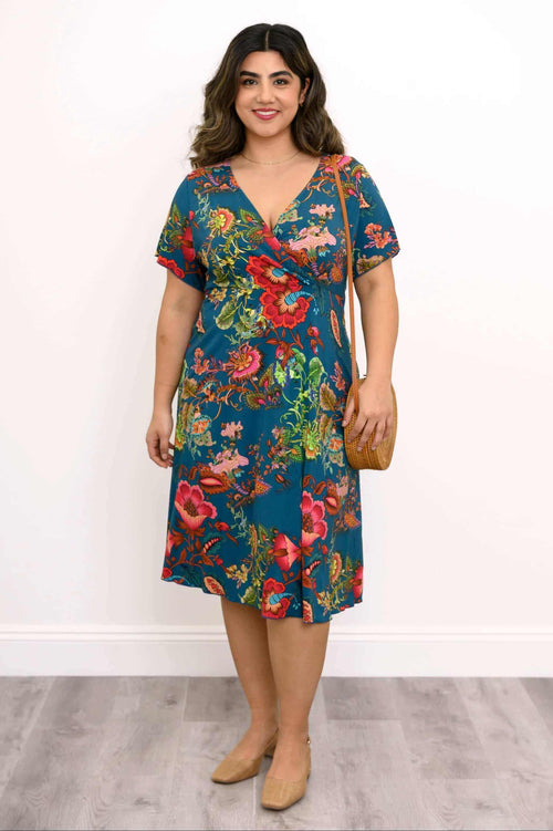 Front view of a woman wearing a teal floral bamboo wrap dress with a crossbody bag