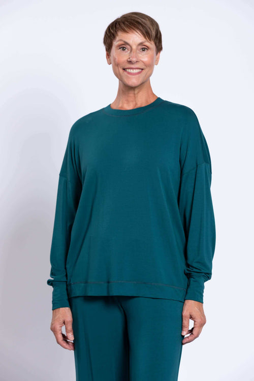 Front view of woman wearing a teal long sleeve bamboo crew neck top