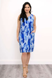 Front view of a woman wearing a sleeveless blue tie-dye shift dress with pockets