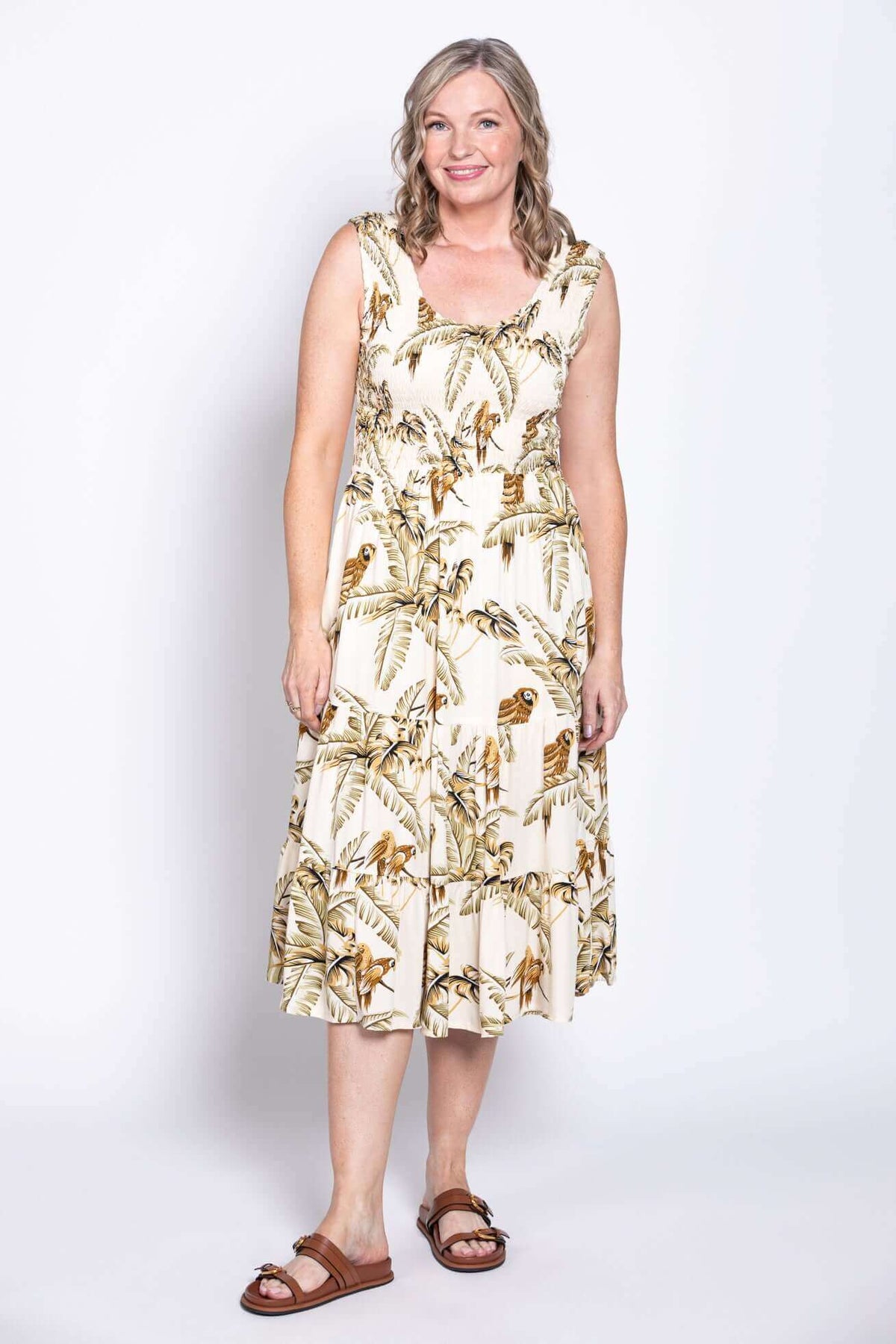 Front view of woman wearing a cream tropical print midi dress with wide straps