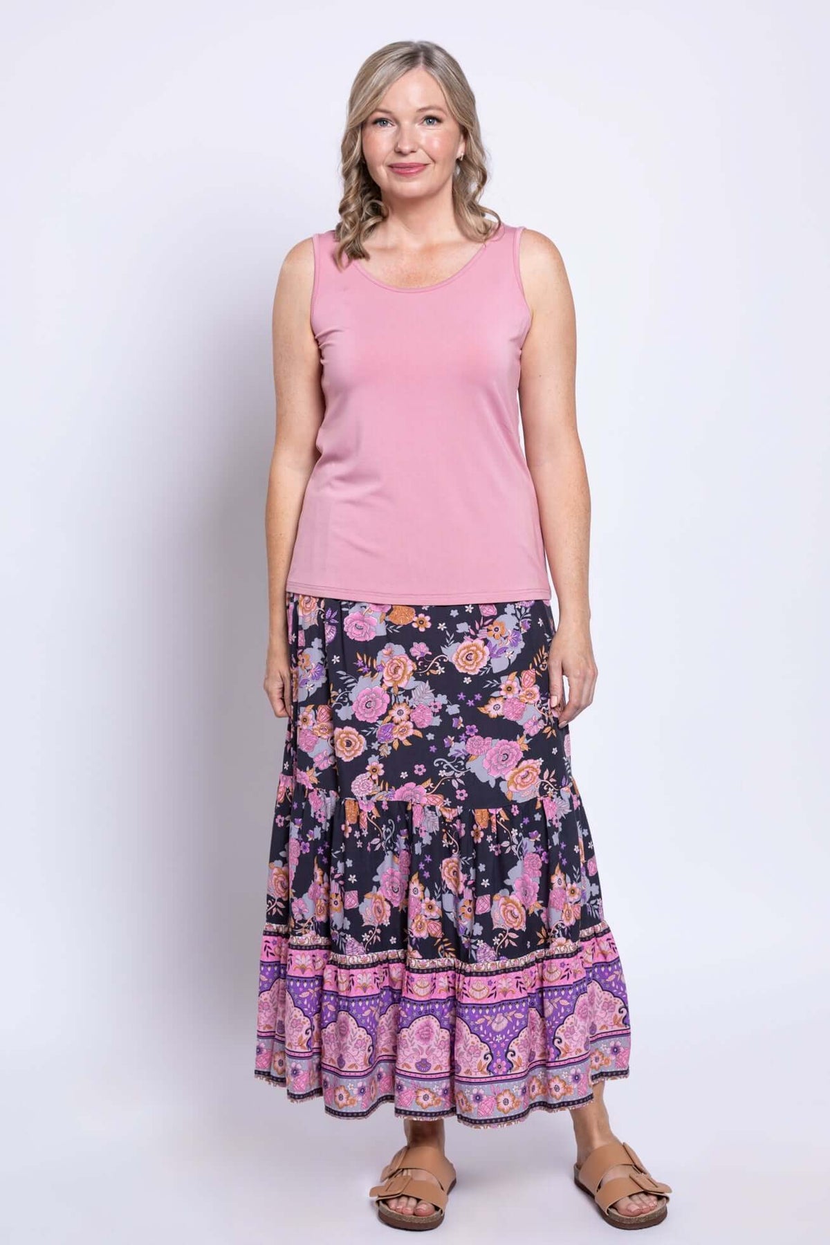 Front view of woman in Tibby floral maxi skirt paired with a pink tank top