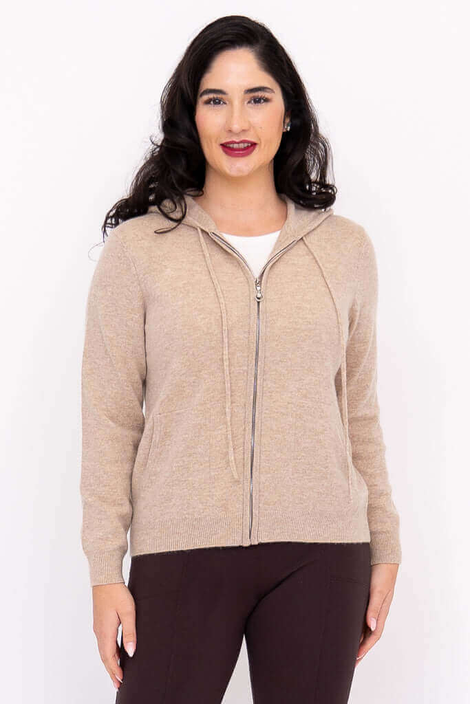 Woman wearing a beige zip-front hoodie with hood down, front view