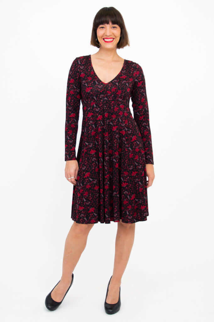 Front view of woman wearing black and red floral fit and flare dress with long sleeves