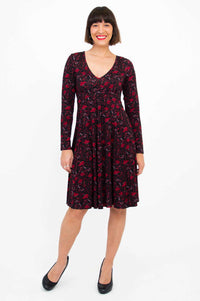 Front view of woman wearing black and red floral fit and flare dress with long sleeves