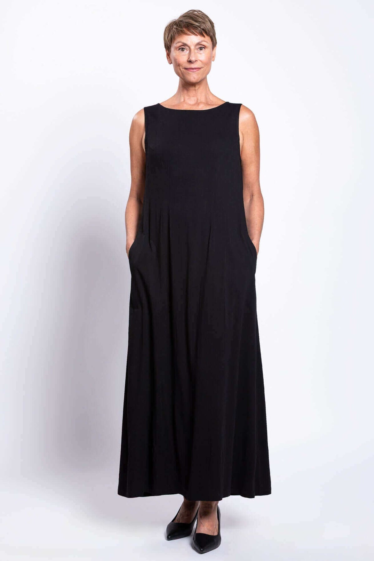 Front view of woman in black ankle-length dress, hands in pockets