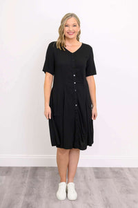 Woman smiling in a black button-up dress with white sneakers, front view