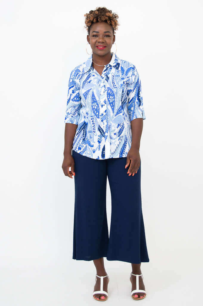 Woman standing in blue and white collared blouse and navy wide trousers, front view