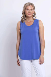 Front view of a woman wearing a blue sleeveless bamboo tank top with white pants
