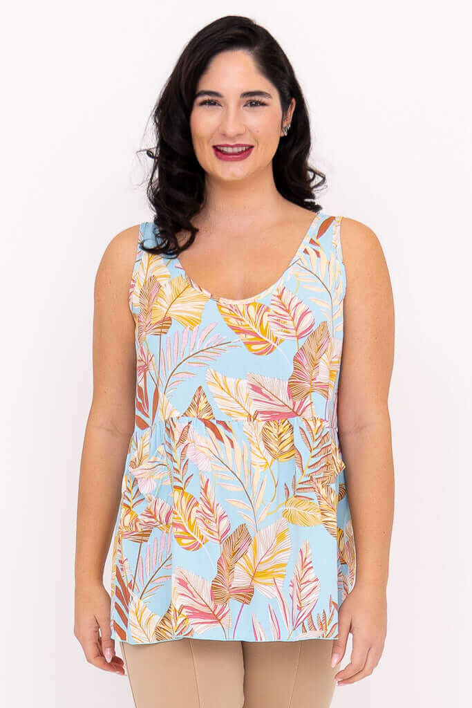 Front view of woman wearing a blue tank top with colorful leaf print