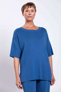 Front view of woman wearing a relaxed blue sweater with short sleeves