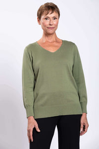 Front view of a woman wearing a green V-neck cotton sweater with black pants