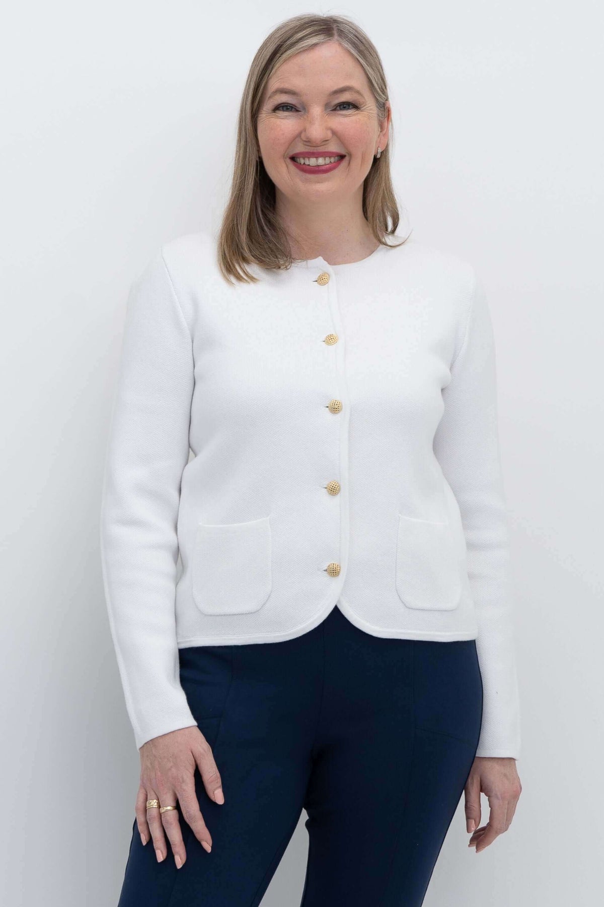Front view of woman wearing ivory cardigan with gold buttons