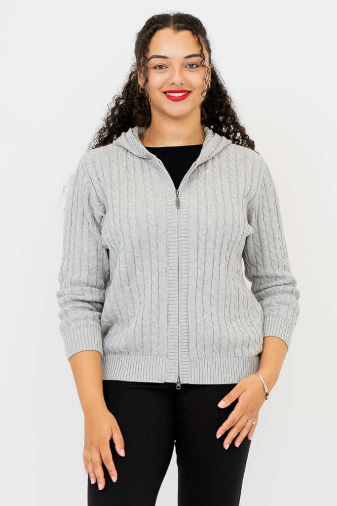 Front view of woman modeling a light grey cable knit zip-up sweater with hood