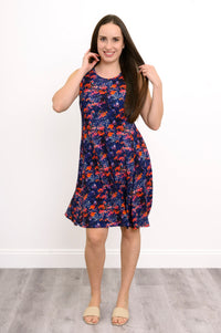 Front view of woman in navy floral sleeveless dress with round neck, posing with hands near hair