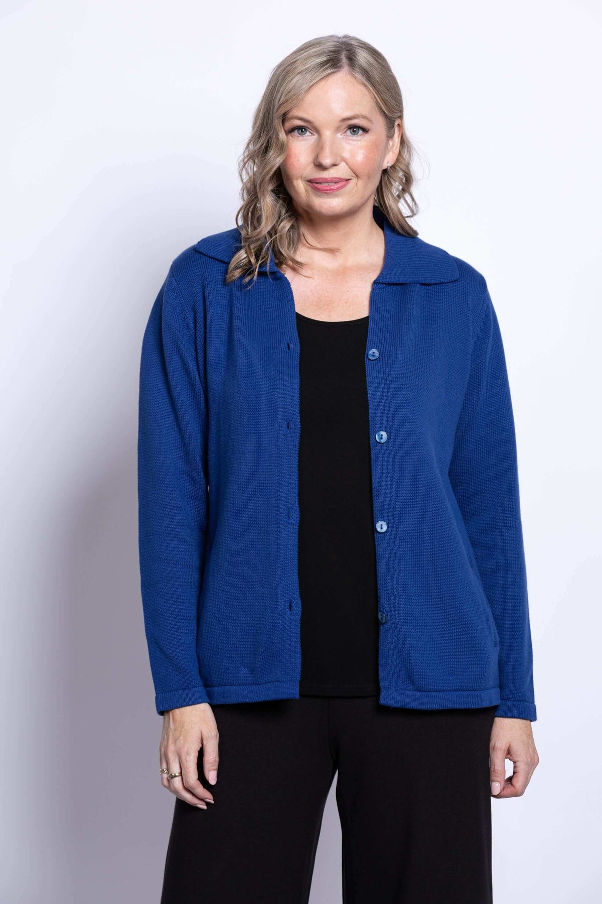 Front view of woman in open royal blue Lily Cardigan layered over black top