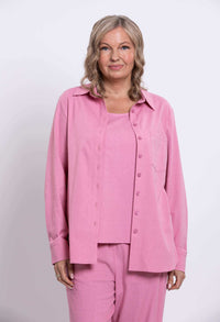 Front view of a woman wearing a relaxed fit pink linen shirt and matching tank top