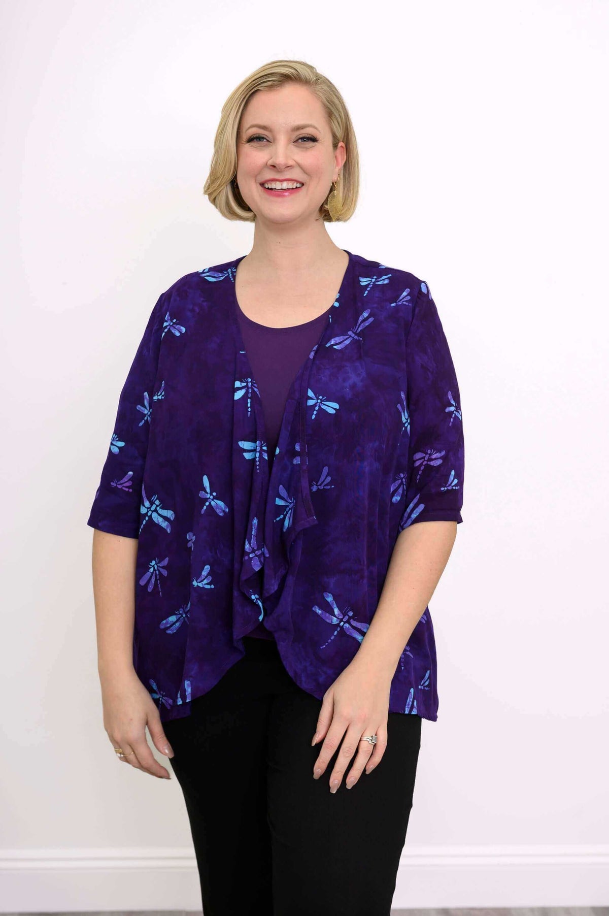 Woman wearing a purple Toucan Jacket with blue dragonfly print, smiling front view