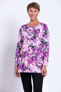 Front view of a woman wearing a long sleeve floral tunic in purple and pink