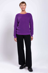 Front view of woman in purple sweater paired with wide-leg black trousers