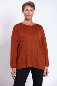 Front view of woman wearing rust Merino wool sweater with long sleeves and relaxed fit