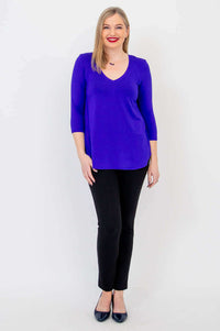 Front-facing woman in sapphire blue V-neck bamboo top and black pants