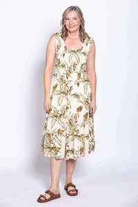 Woman wearing a sleeveless midi dress with tropical palm and bird print, standing front facing