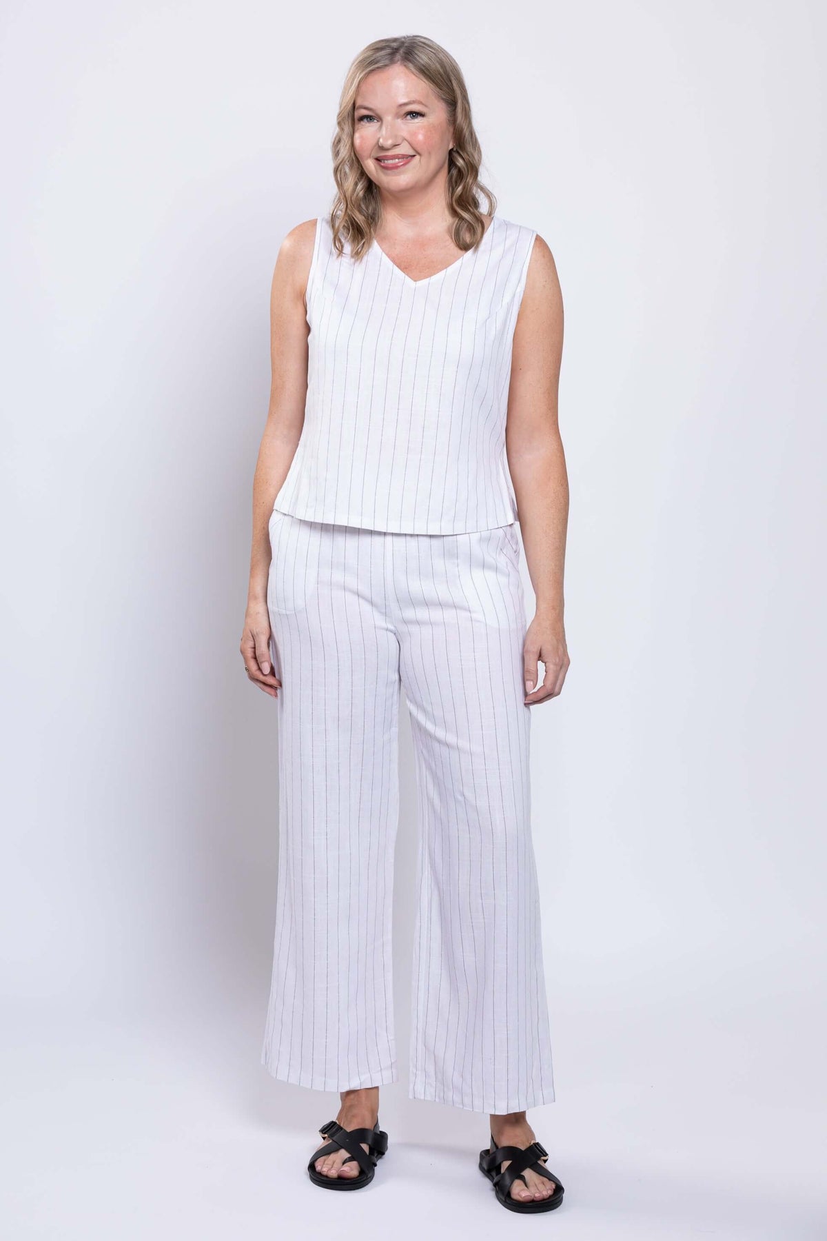 Front view of woman wearing white wide-leg striped pants and matching sleeveless top