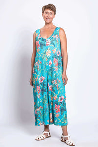 Front view of a woman wearing a sleeveless turquoise floral jumpsuit