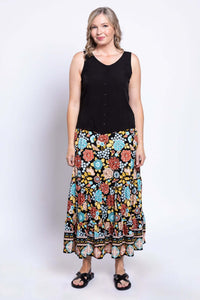 Woman standing front-facing in a vibrant floral maxi skirt and black sleeveless blouse