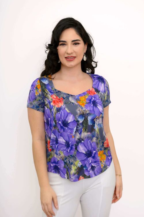 Woman wearing a vibrant purple floral short sleeve top, front view